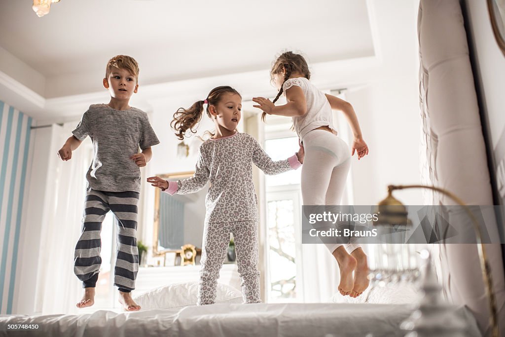 Group of children having fun while jumping on a bed.