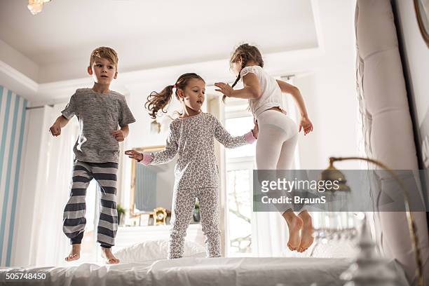 group of children having fun while jumping on a bed. - jumping on bed stockfoto's en -beelden