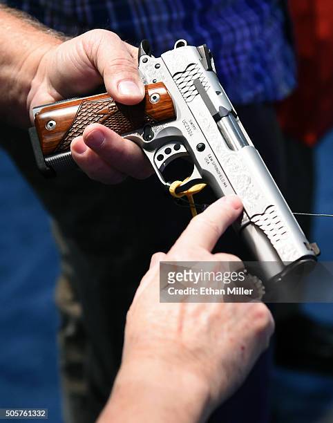 Convention attendees look at a model SW1911 Pro Series 9mm handgun at the Smith & Wesson booth at the 2016 National Shooting Sports Foundation's...