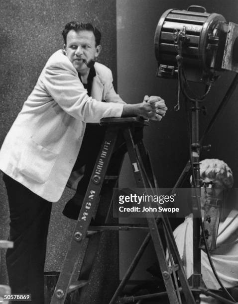 Director Joseph Mankiewicz smoking pipe while standing on ladder while directing Julius Caesar.