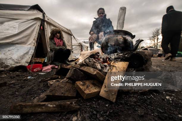 Migrants get warm around a brazier in the migrants camp of Grande-Synthe, near Dunkirk, on January 20 where almost some 2,500 migrants and refugees...