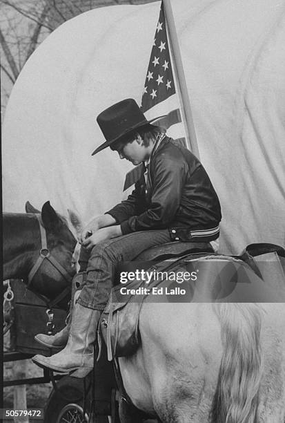 Weary boy sitting sidesaddle atop horse during a rest stop while reenacting 1,000-mile Trail of Tears journey that Cherokees traveled 150 years ago....