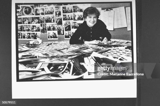 People magazine photo researcher Mary Fanette rummaging through photographs piled on her desk for Best-and Worst-Dressed issue at Time-Life building.