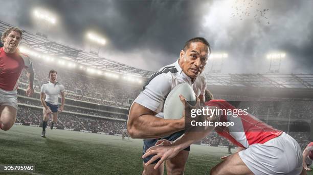 rugby player running with ball whilst being tackled during game - rugby tackle stockfoto's en -beelden