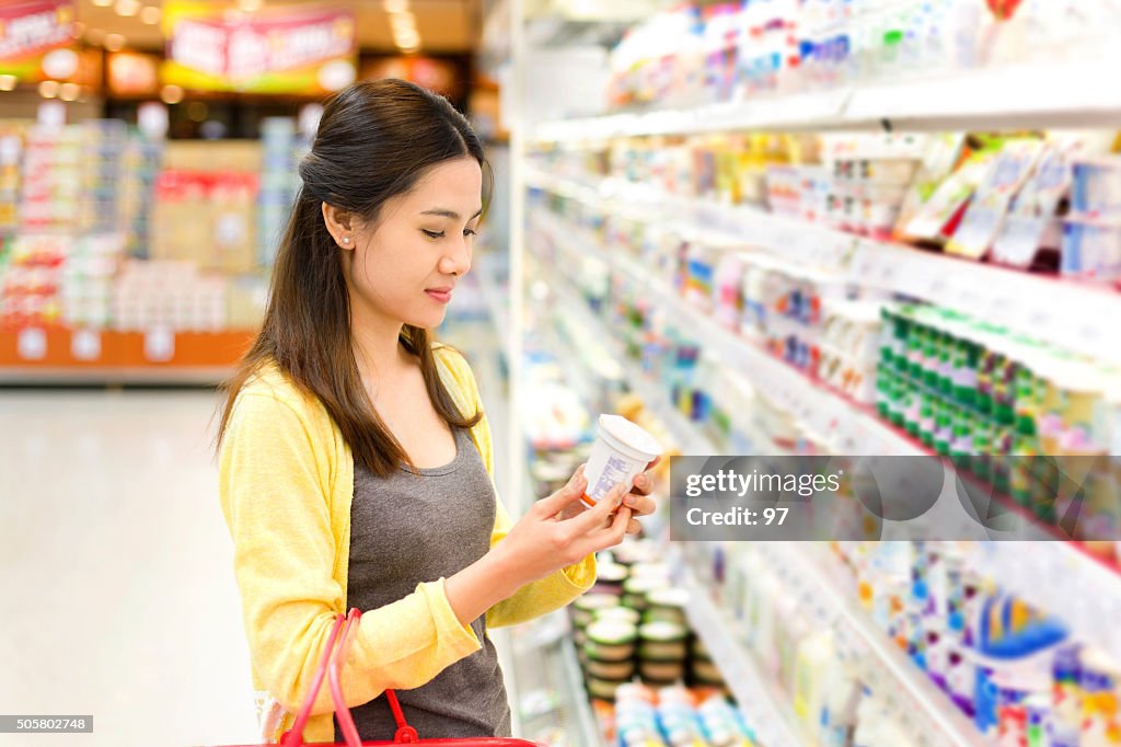 Asian woman buys in the supermarket yogurt