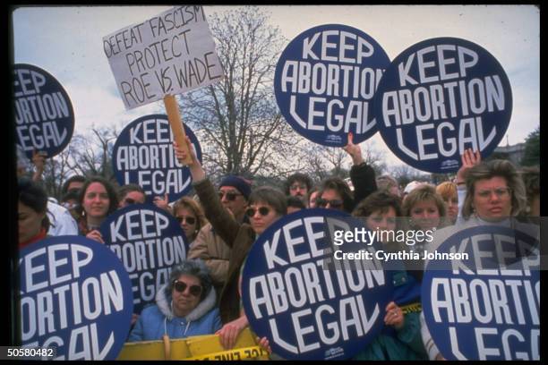 Demonstrators carrying giant keep abortion legal buttons & ...protect Roe vs. Wade sign during huge pro-choice march.