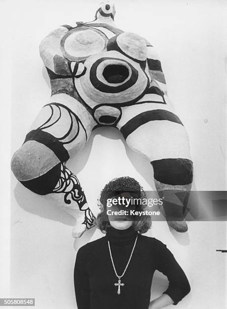 Portrait of French artist Niki De Saint-Phalle standing in front of one of her famous 'Nanas' sculptures, circa 1965.