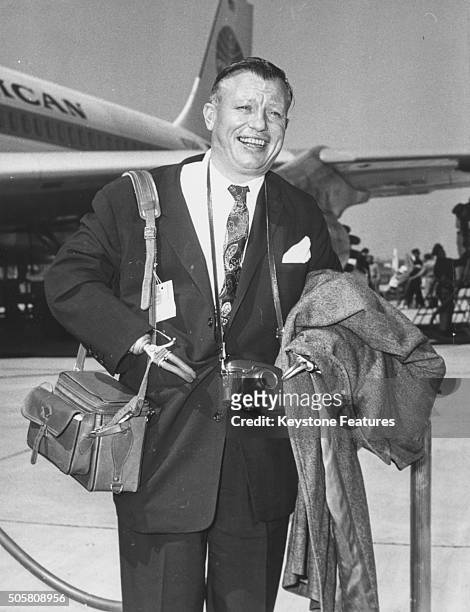 Academy Award winning actor Harold Russell smiling as he arrives at the airport carrying his luggage, in the country to take part in the Assembly of...