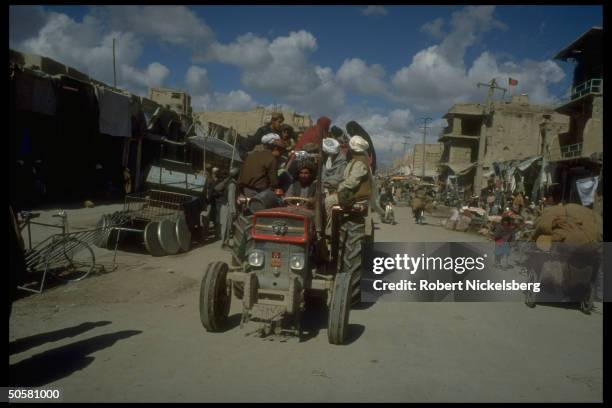 Passenger crowded tractor - like vehicle in bustling market area of war torn city largely destroyed in 10 yrs. Of govt. Vs. Mujahedeen fighting.