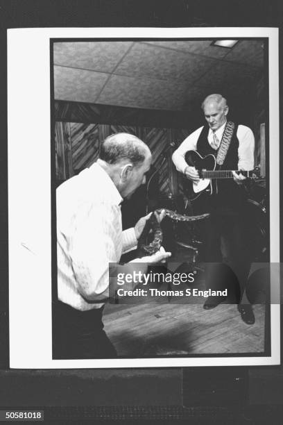 Church leader Dewey Chafin playing guitar & singing as Ray McCallister handles a timber rattlesnake during worship service at the Church of the Lord...