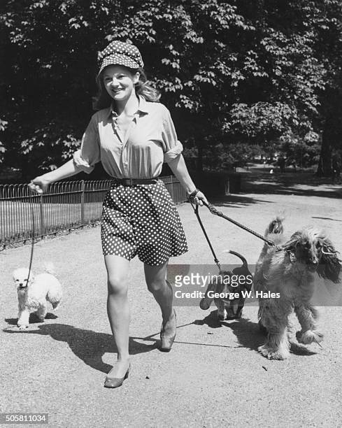 Actress Anna Palk smiling as she walks her three pet dogs in Hyde Park, London, July 20th 1967.