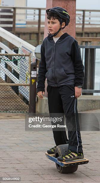 Young boy wearing a helmet rides an unusual one-wheel all-terrain "hoverboard" on January 17, 2016 in Pismo Beach, California. Because of its close...