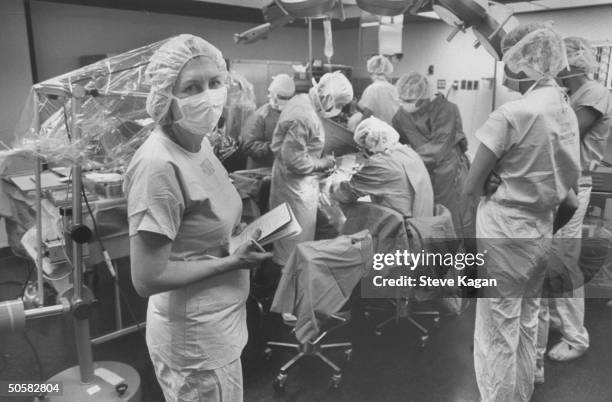 Chicago bureau chief Giovanna Breu in surgical duds holding pad & pencil while covering ear implant operation for magazine story; University of Iowa...