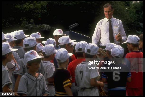 Pres. Bush talking to Polish Little League players in white baseball caps, during his visit to Poland.