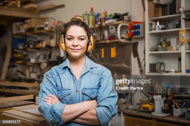 female carpenter wearing her yellow earmuffs. - ohrenschützer stock-fotos und bilder