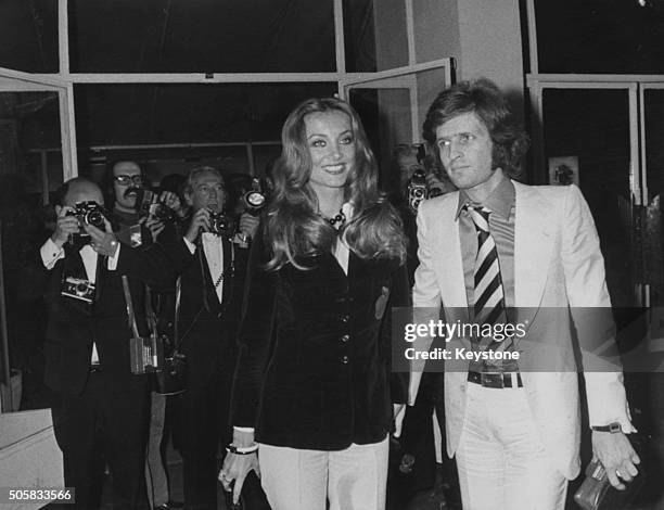 Actress Barbara Bouchet holding hands with Paolo Pazzaglia in front of a bank of press photographers, as they attend the Cannes Film Festival,...