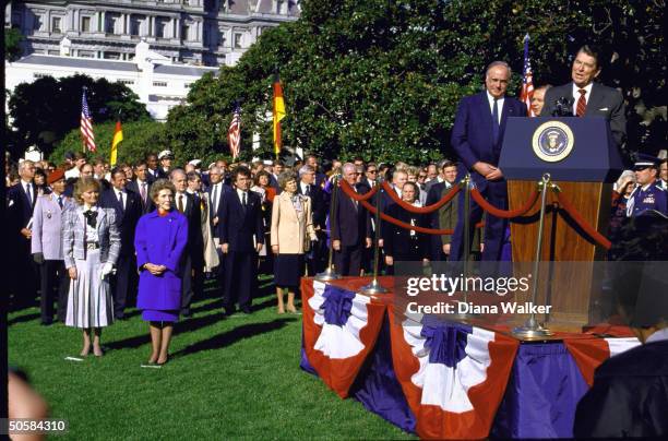 Pres. Reagan & W. German Chancellor Kohl on dais at WH lawn fete, w. Their wives Nancy & Hannelore in fore of crowd in attendance.