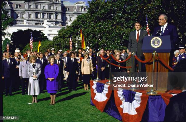 Pres. Reagan on dais w. W. German Chancellor Kohl at WH lawn fete, w. Their wives Nancy & Hannelore in fore of crowd in attendance.