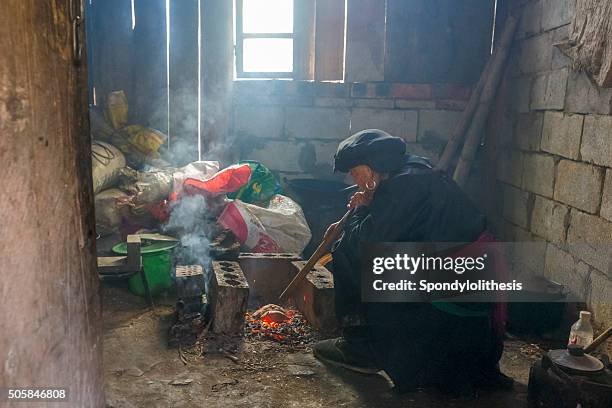 alte frau blasen pipe zu backen die süßen kartoffeln, china - bauer pfeife stock-fotos und bilder