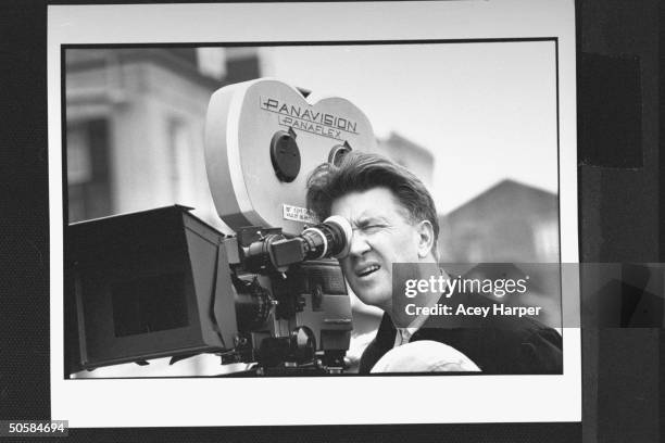 Closeup of movie director David Lynch, looking through Panavision Panaflex movie camera as he directs filming of Wild at Heart on street location.