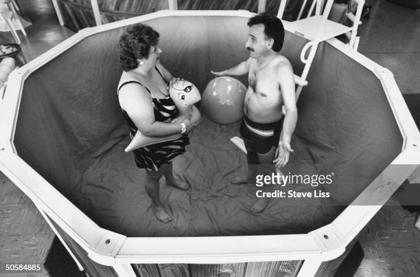 Homeowners Joe Paladino & wife Cheryl posing in small, empty above-ground pool at friend's house; Joe was featured on the TV show America's Funniest...