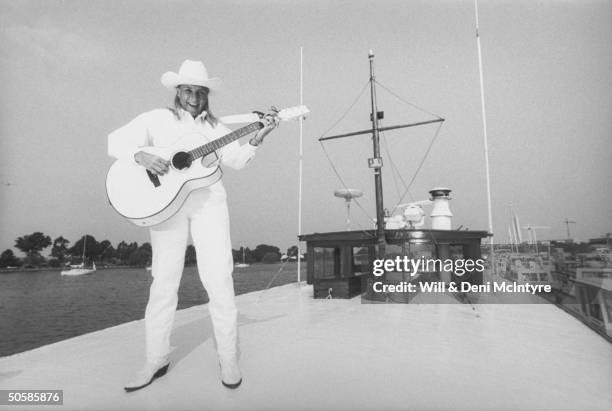 Country singer Jett Williams, illegitimate daughter of late singer Hank Williams Sr., wearing white cowboy hat, shirt & jeans as she plays a white...