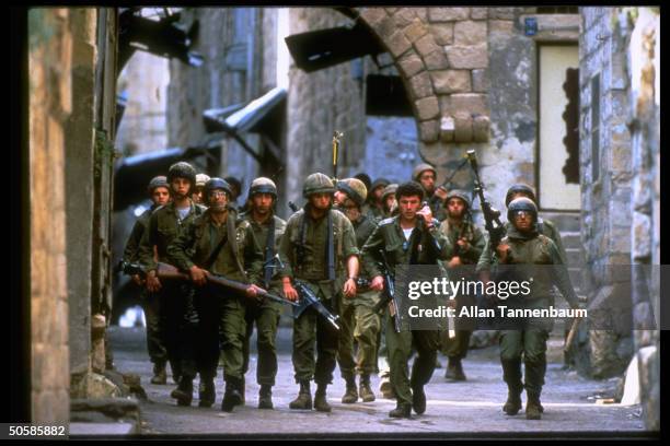 Group of armed Israeli soldiers walking through streets; Nablus. Israeli-occupied West Bank.