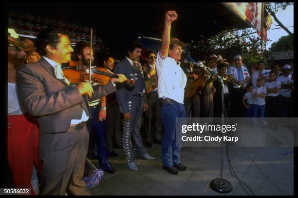 Right-wing ARENA ldr. Roberto D'Aubuisson raising clenched fist in party salute, singing w. Mariachi band, campaigning for March 10 natl. Elections.