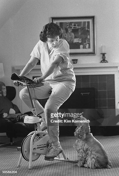 San Francisco Mayor & Dem. Gubernatorial hopeful Dianne Feinstein working out on stationary bike w. Cocker spaniel Maotai; at home.
