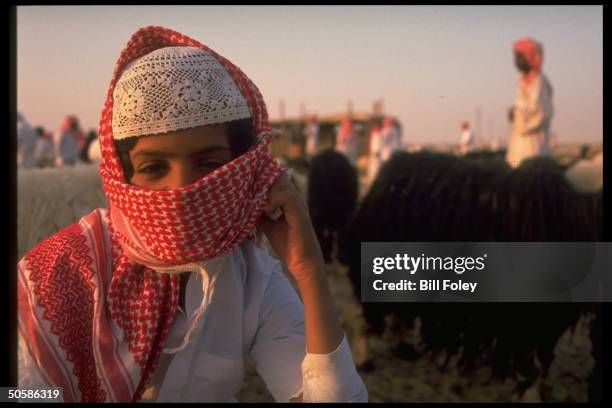 Young kaffiyeh-clad boy shepherd minding his flock, at camel & sheep market .