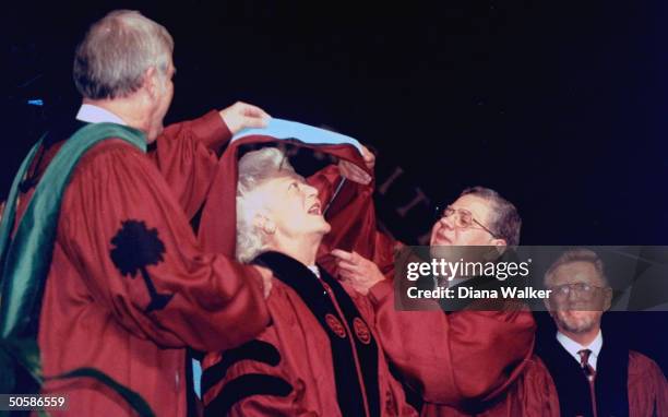 University of South Carolina officials lifting academic sash over 1st Lady Barbara Bush's head as she attends graduation ceremonies, May 1990.