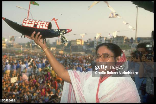 Awami League ldr. Sheik Hasina Wazed on stump, holding boat , during crowded election campaign rally.