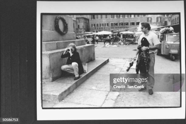 Actress Kelly Curtis squatting while shooting picture at Campo dei Fiori while husband Scott Morfee watches & holds her things; La Carbonara...