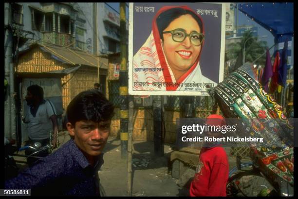 Local youths in front of election campaign poster bearing smiling image of Awami League ldr. & cand. Sheik Hasina Wazed.