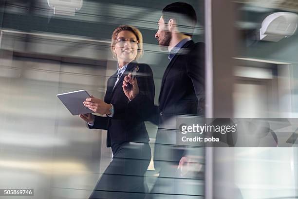two business coworkers walking along elevated walkway - onscherp stockfoto's en -beelden