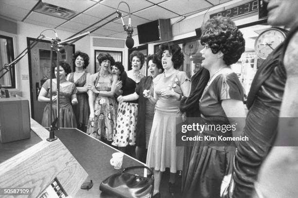 Ten members members of the Ethel Merman Memorial Choir, wearing wigs & dresses as they imitate their idol by belting a rendition of one of the songs...