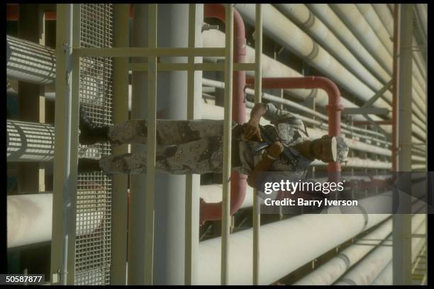 Armed security guard poised by pipelines & port facilties at Saudi Aramco oil refinery & loading terminal at Ras Tanura, Saudi Arabia.