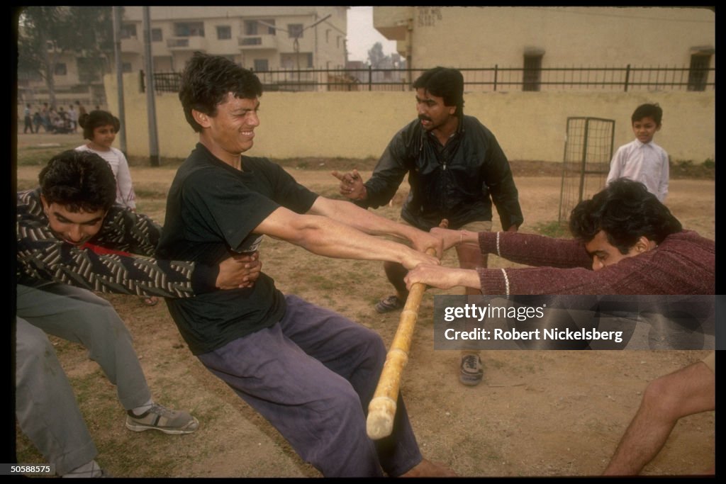 Stick fighting youths in tug of war exer