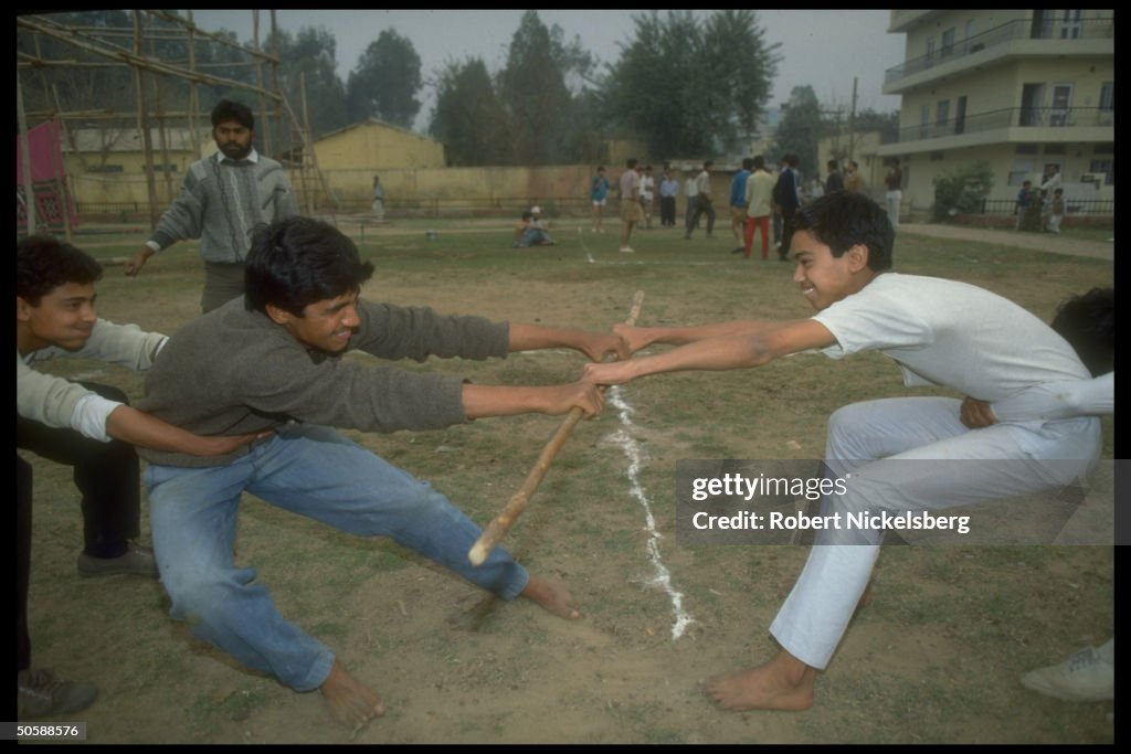 Stick fighting youths in tug of war exer
