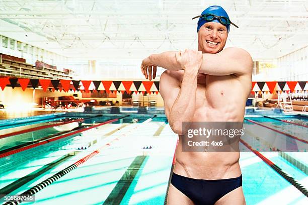 fröhlich mann stretching am swimmingpool - young men in speedos stock-fotos und bilder