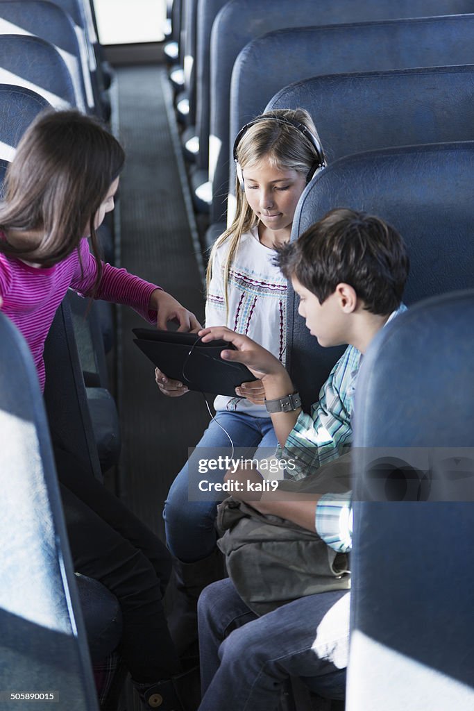 Crianças no autocarro escolar com tablet digital