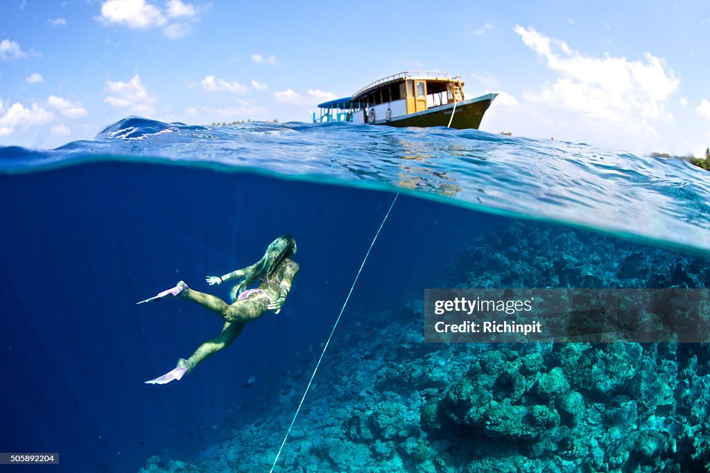 Woman swims towards boat from the anchor