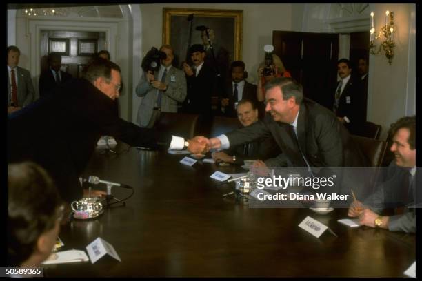 Pres. Bush reaching over table to shake hands w. Soviet Mideast envoy Yevgeny Primakov, mtg. In WH Cabinet Rm.