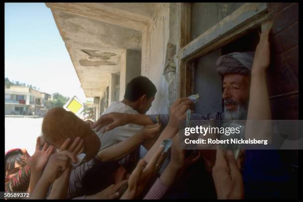 Bread seller being mobbed by paper money-thrusting customers in Kabul, Afghanistan.