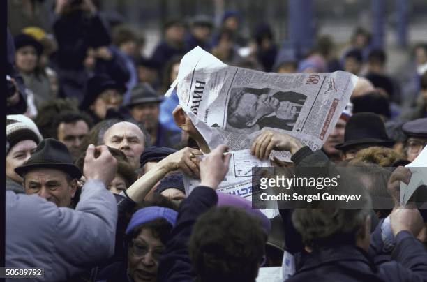 Supporters of Boris Yeltsin rallying for reform-minded, opposition maverick, waving newspapers bearing his image, at Luzhniki stadium election event.
