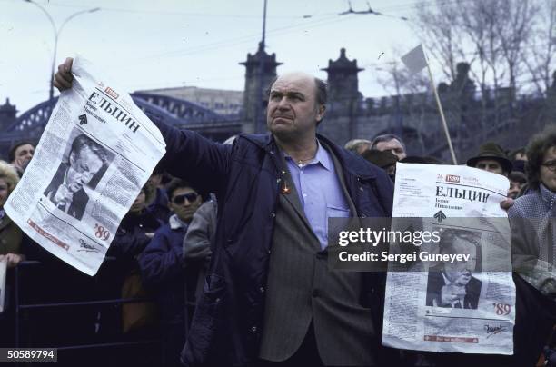 Supporters of Boris Yeltsin rallying for reform-minded, opposition maverick, waving newspapers bearing his image, at Luzhniki stadium election event.