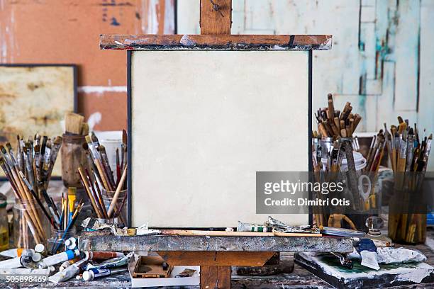 blank art canvas in mess artist's studio - schildersdoek stockfoto's en -beelden
