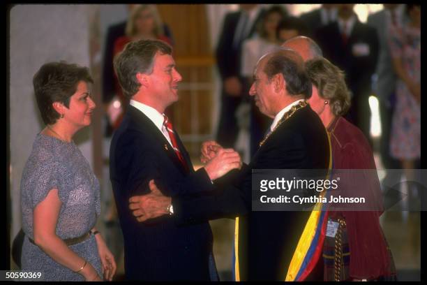 Dan Quayle embracing inaugural-sashed Pres. Carlos Andres Perez, flanked by others attending taking-of-office ceremony.