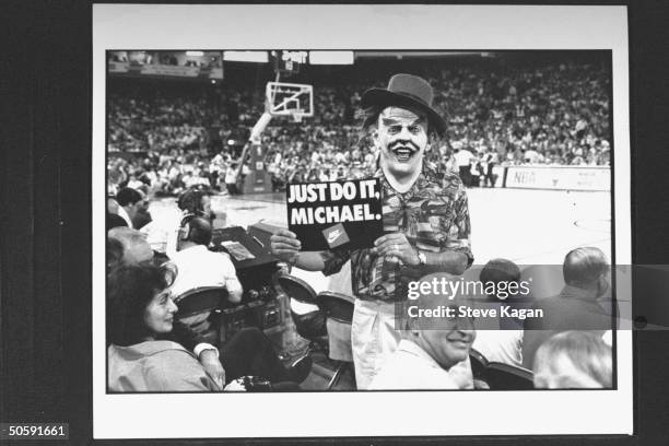 Man wearing a Jack Nicholson Joker mask of Batman movie fame as he holds up a JUST DO IT, MICHAEL. Sign in the bleachers as he exhorts Chicago Bulls'...