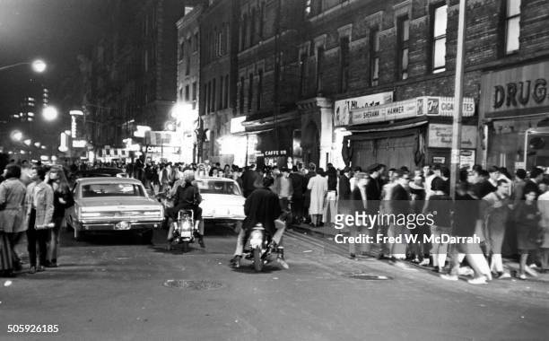Nighttime view , of pedestrians and cars on MacDougal Street , in Greenwich Village, New York, New York, May 21, 1966. In the center is the awning of...